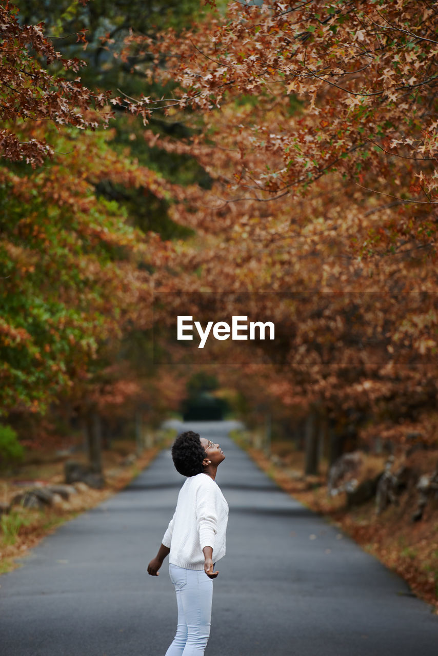 Rear view of woman standing on footpath during autumn