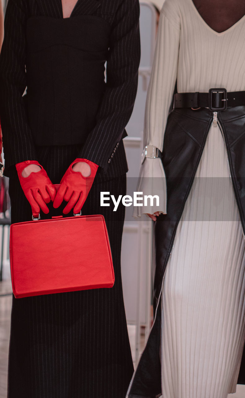 Fashion details of a knitted warm white dress, red leather gloves, handbag. fashion models posing