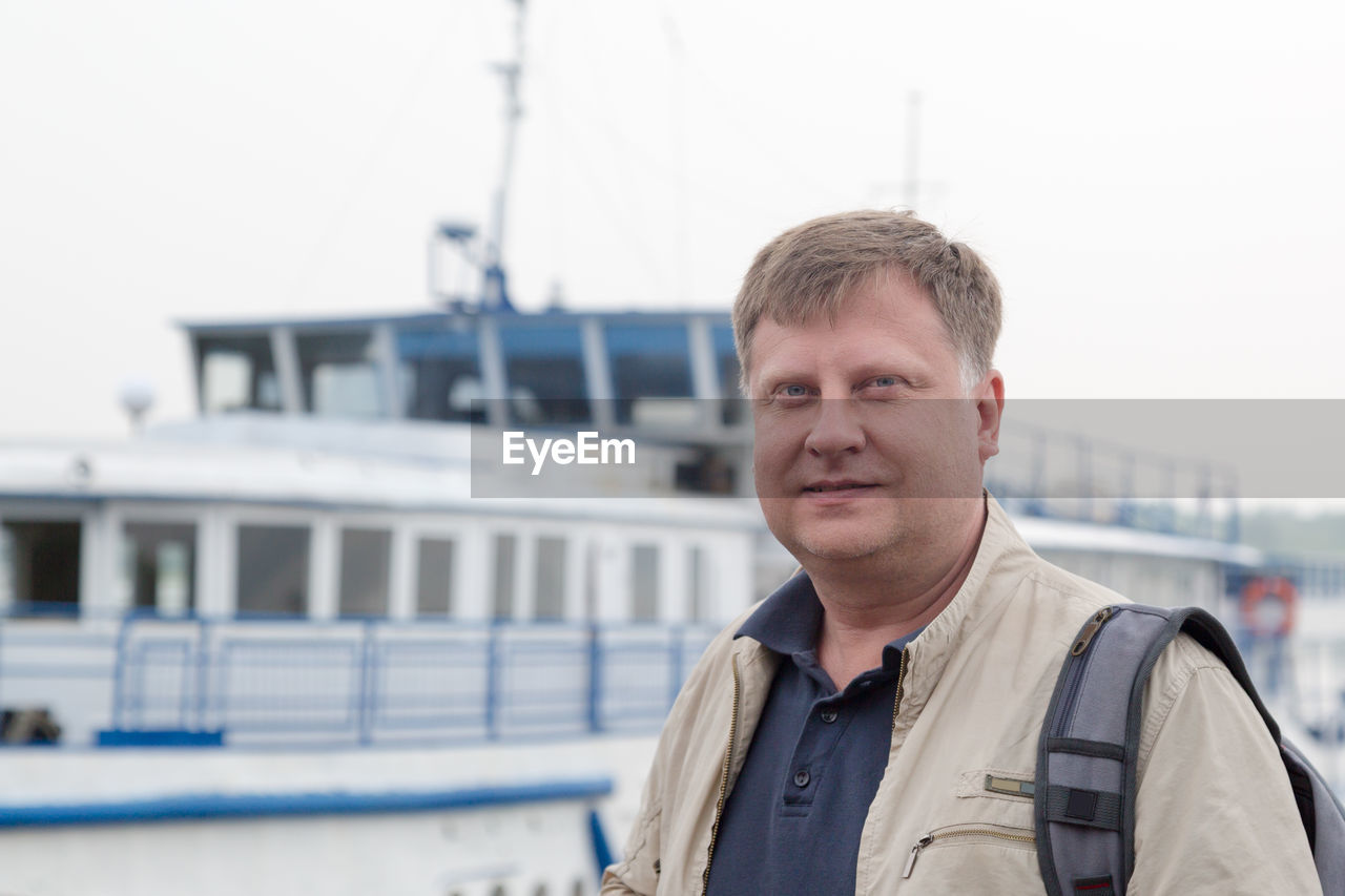 An adult male sailor with a backpack returned home after a long voyage.