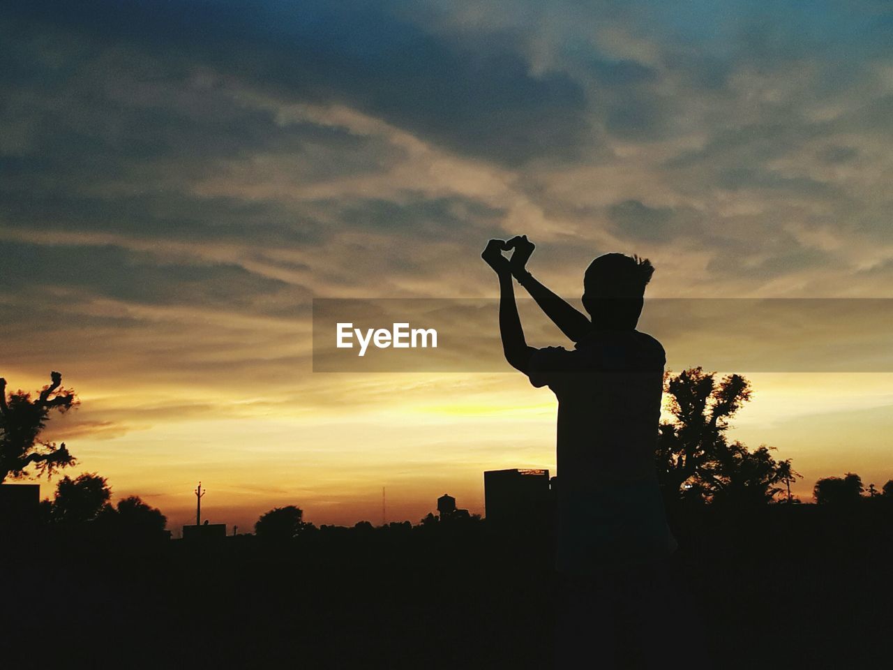 Silhouette man shaping heart against sky during sunset