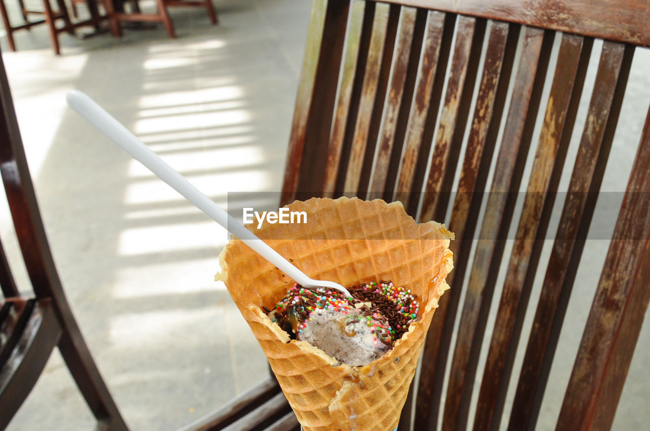HIGH ANGLE VIEW OF ICE CREAM CONE ON WOODEN TABLE