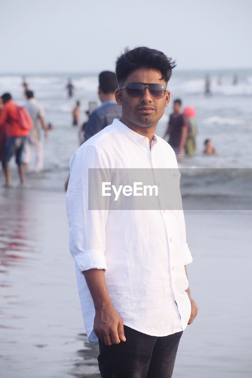 Portrait of young man standing at beach