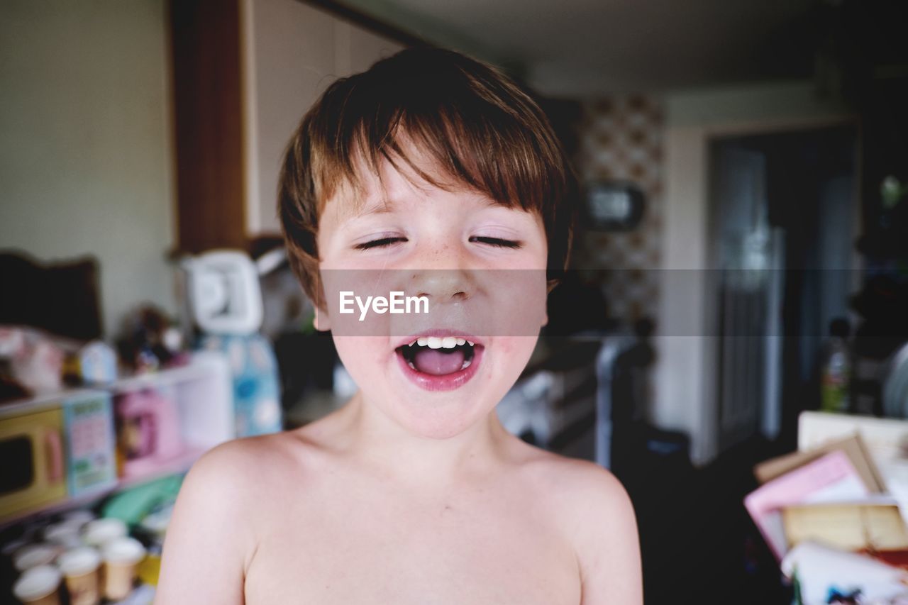 Close-up of cute shirtless boy smiling at home