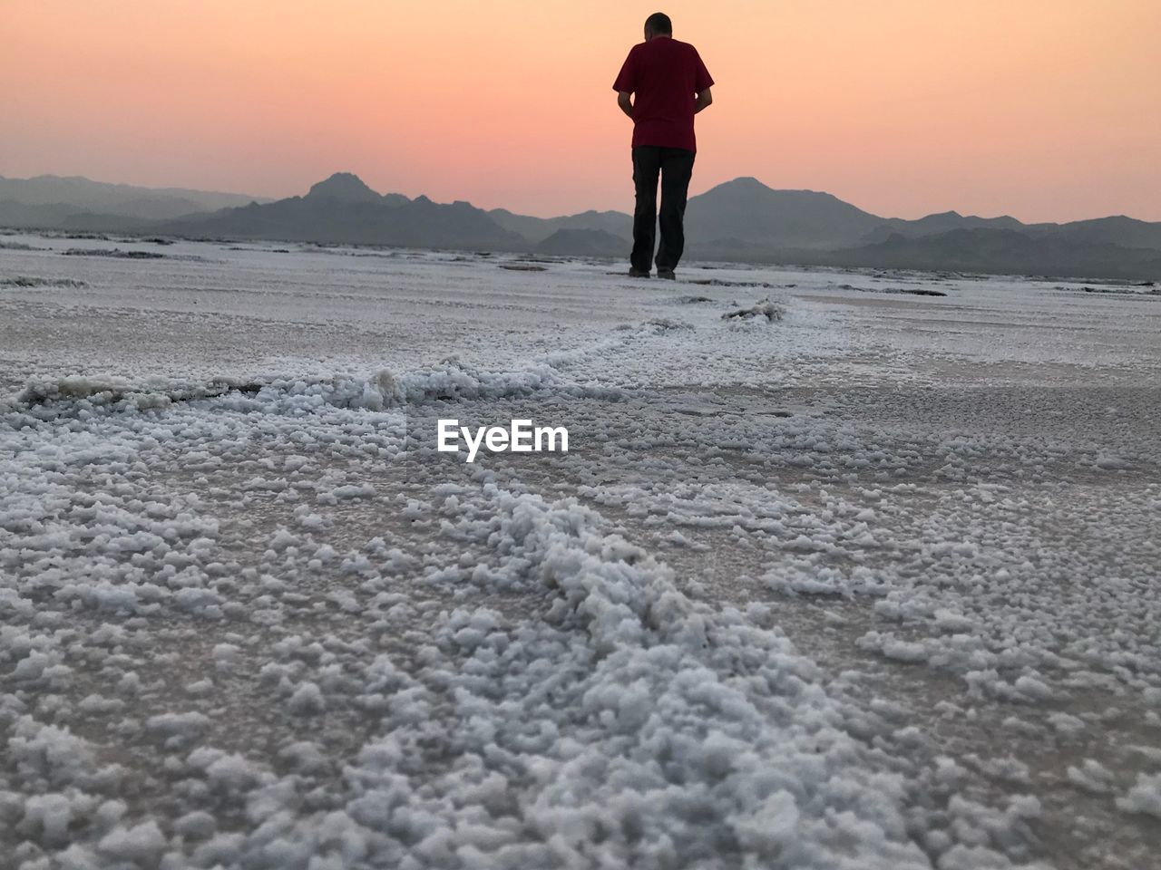 Rear view of man standing at bonneville salt flats during sunset