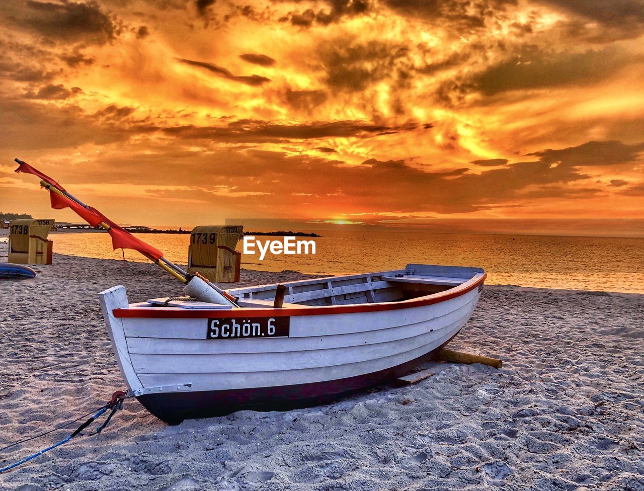 BOAT MOORED ON SEA AGAINST SKY DURING SUNSET