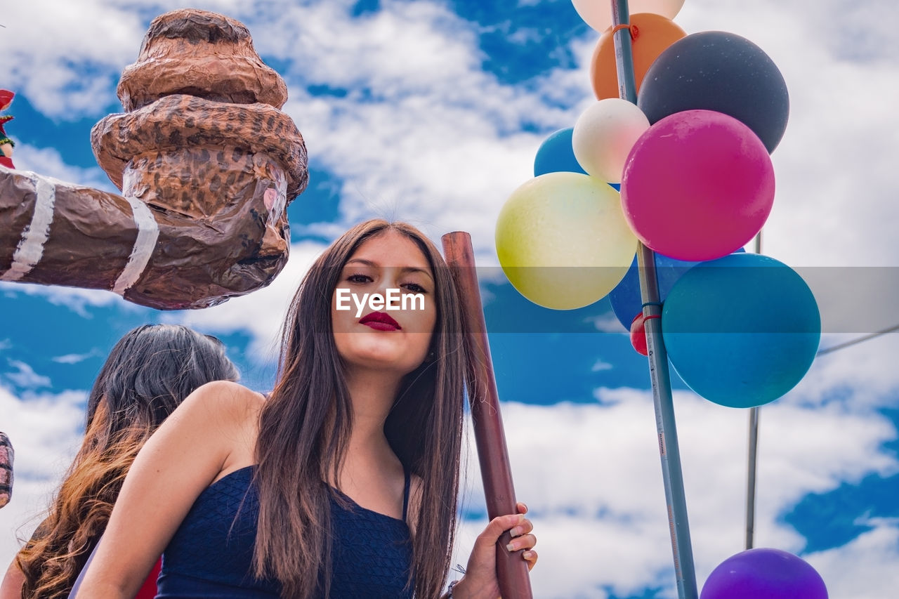 PORTRAIT OF YOUNG WOMAN HOLDING BALLOONS IN BALLOON