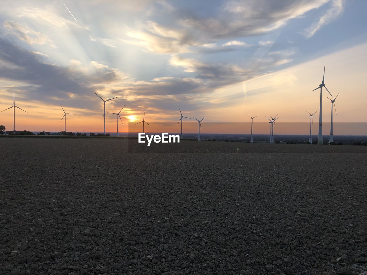 Wind turbines on field against sky during sunset