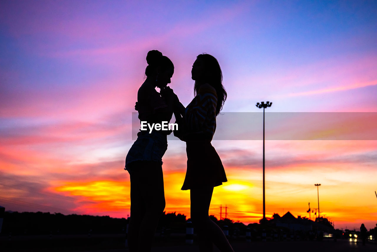 SILHOUETTE PEOPLE STANDING AGAINST ORANGE SKY