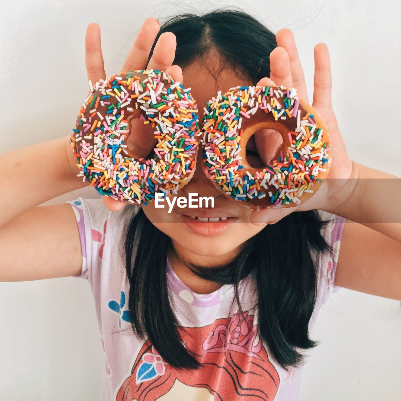 High angle view of girl holding doughnuts in front of her face