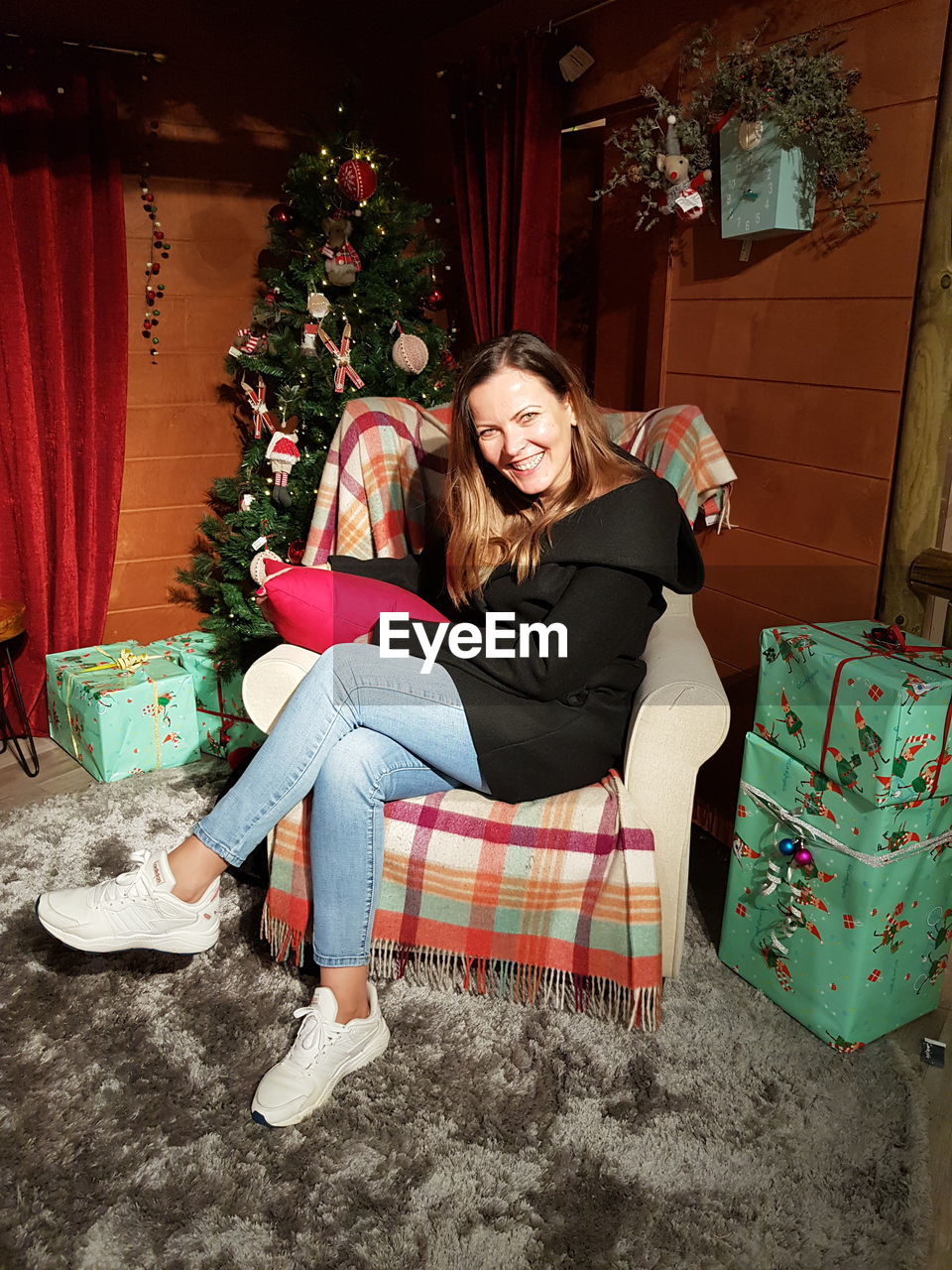 Full length portrait of smiling young woman sitting at home