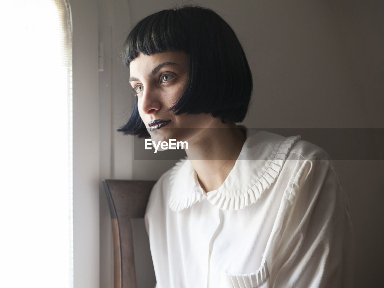 Young woman looking away while sitting by window