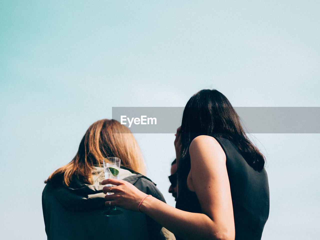 Rear view of women against clear sky on sunny day