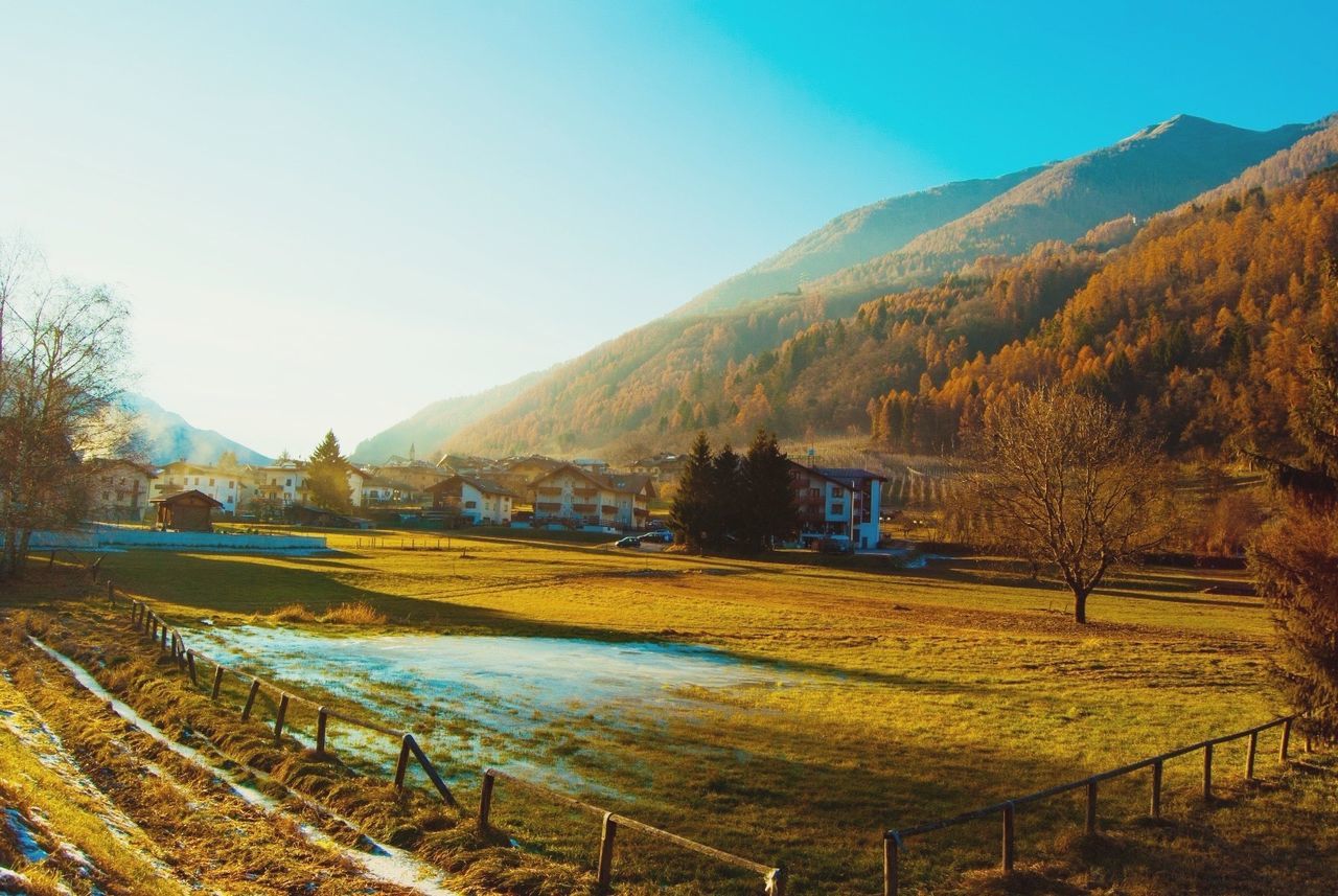 Houses on field by mountains against clear sky