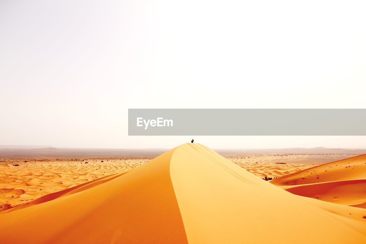 Scenic view of sand dunes against clear sky