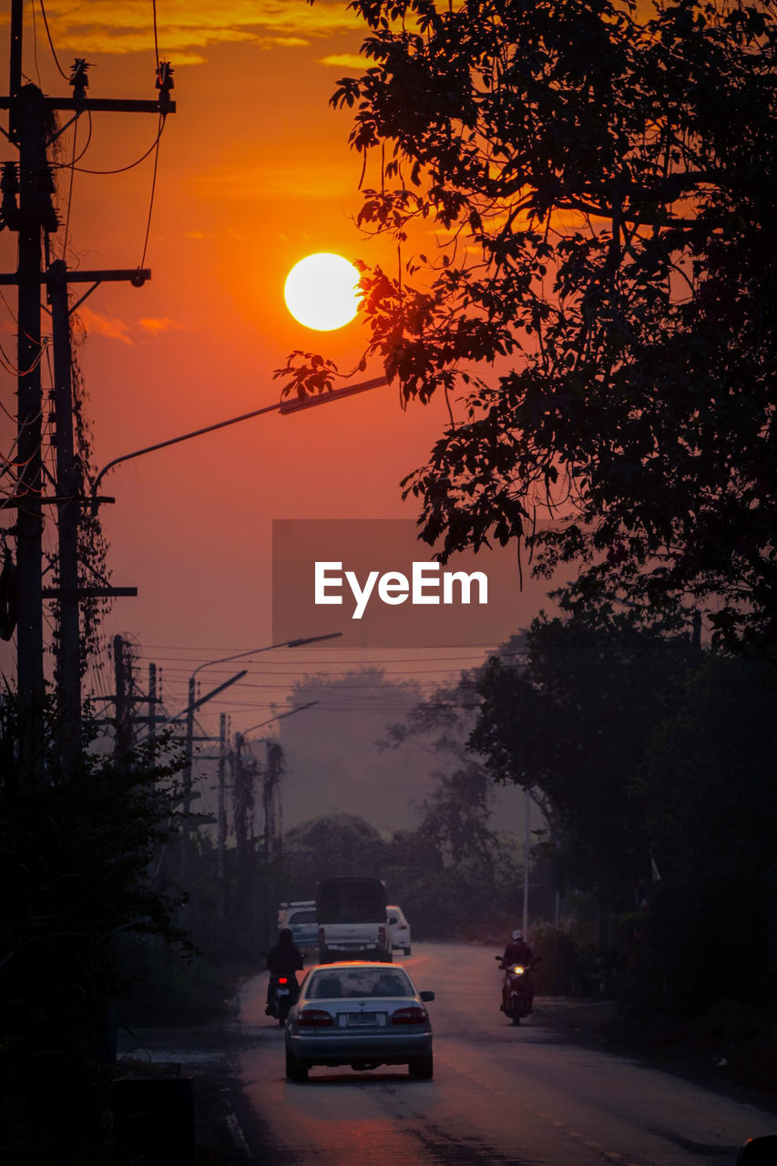 Cars on road against sky during sunset