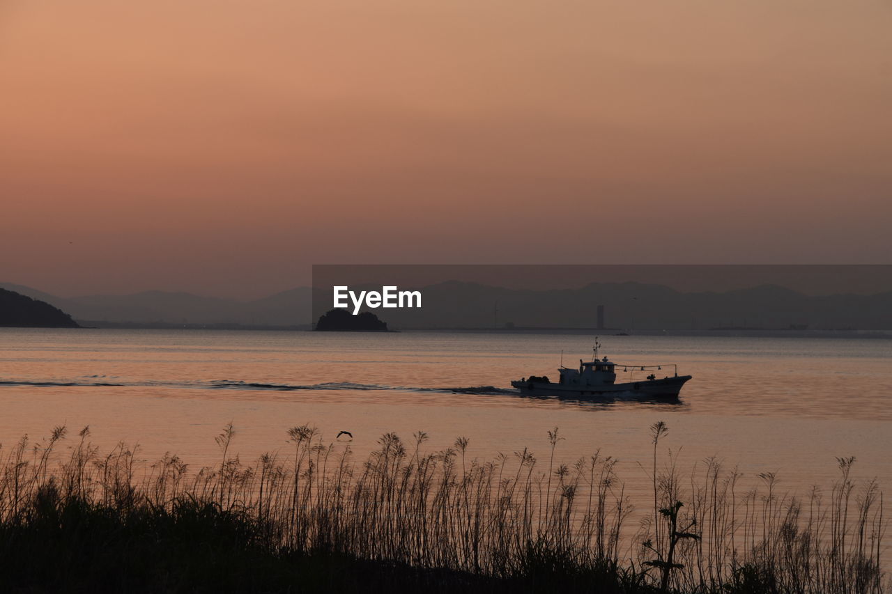 SILHOUETTE BOATS IN SEA AGAINST ORANGE SKY