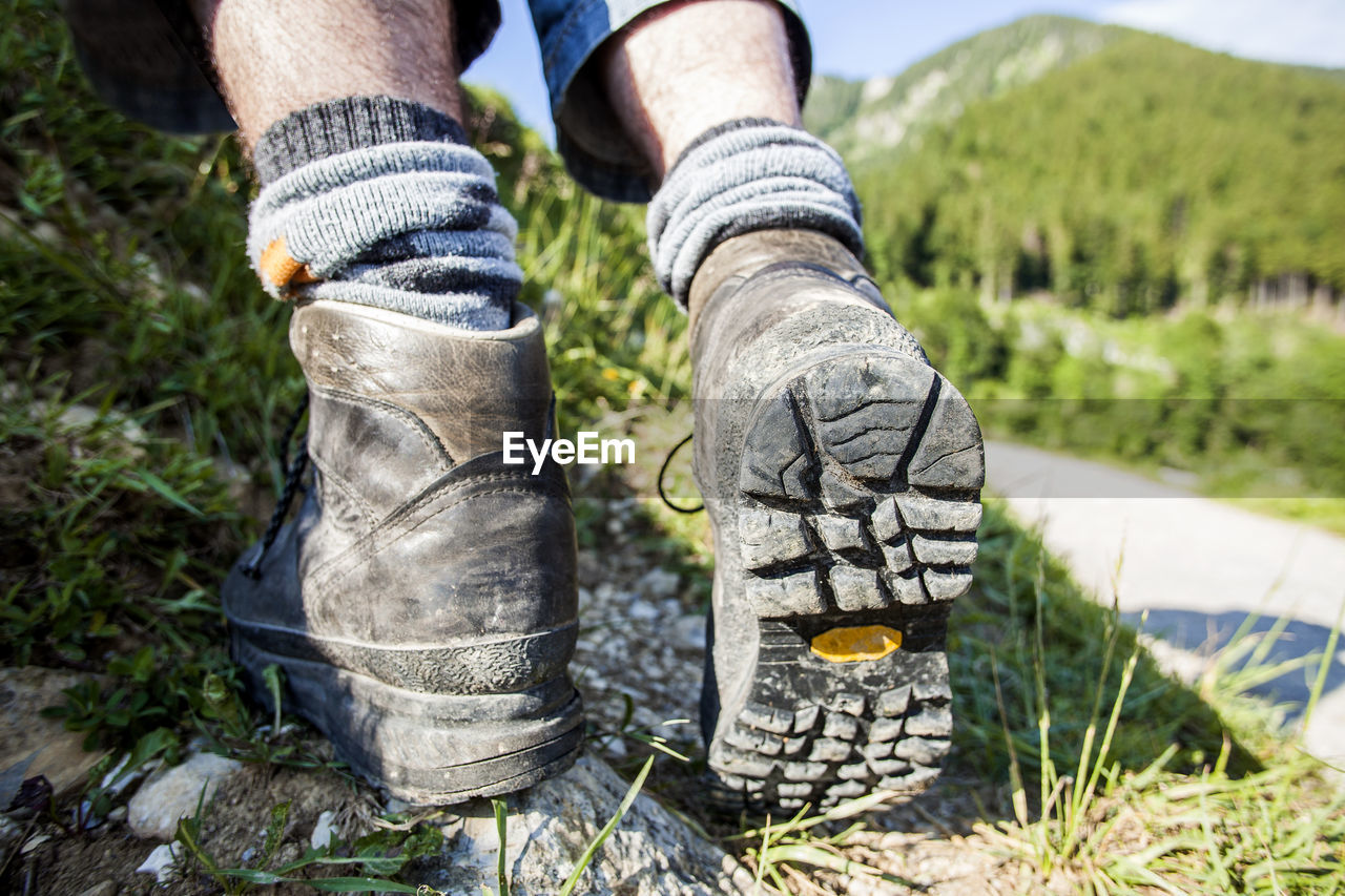 one person, shoe, plant, footwear, nature, low section, human leg, grass, limb, human limb, leisure activity, adult, day, green, outdoors, lifestyles, hiking, spring, land, tree, men, activity, environment, human foot, walking, landscape, casual clothing, sports, sock, sunlight, standing, dirt