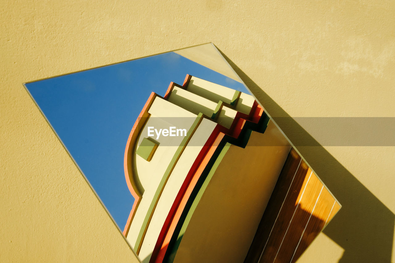 Reflection of building on mirror against yellow wall