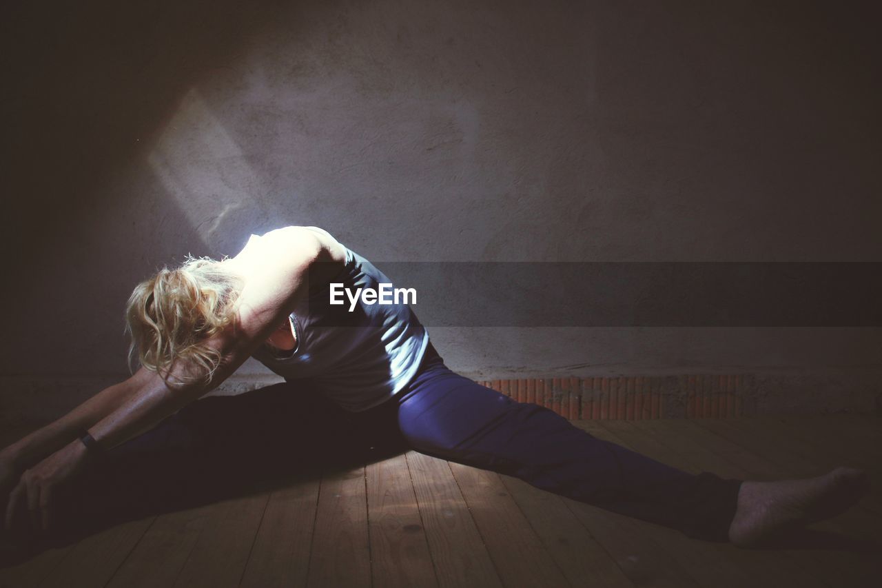 Woman stretching on hardwood floor at home