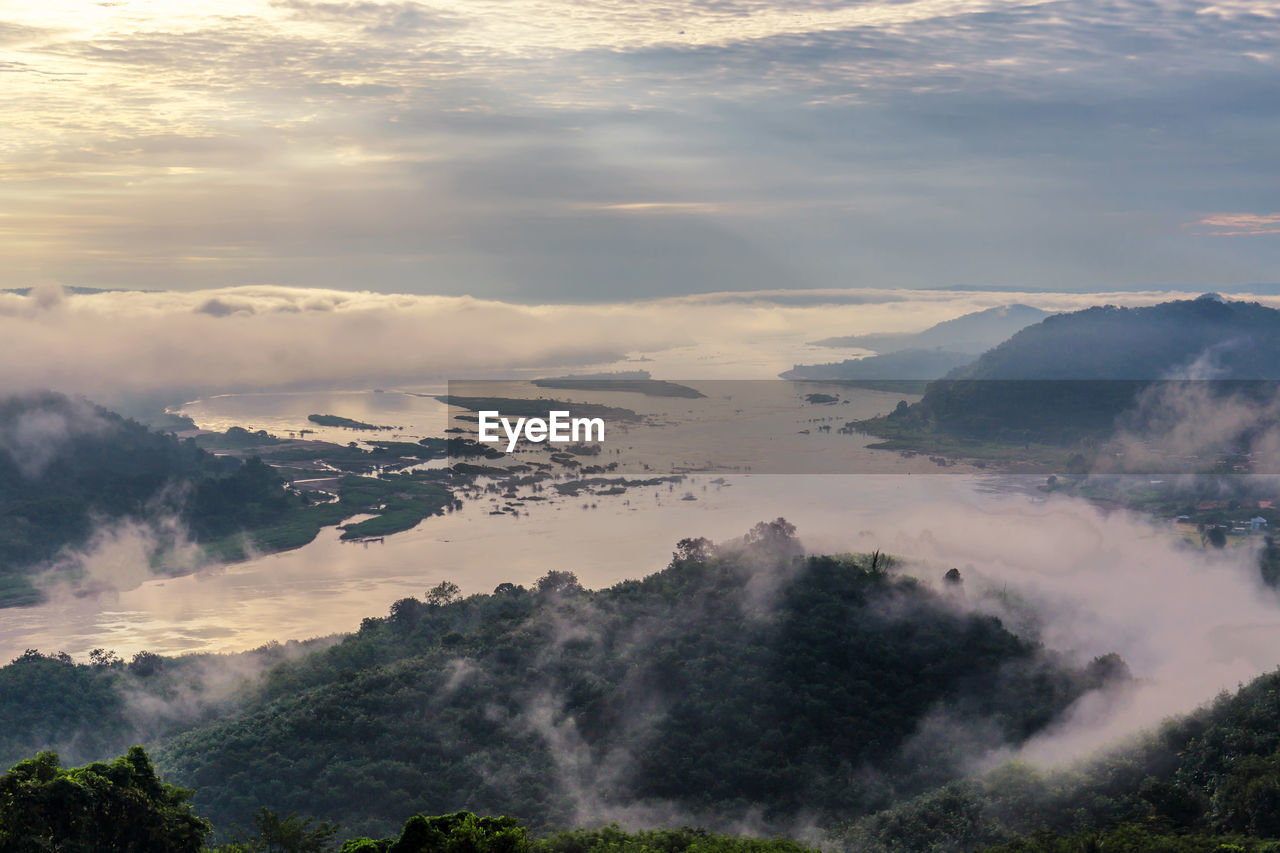 High angle view of sea by mountains during sunset