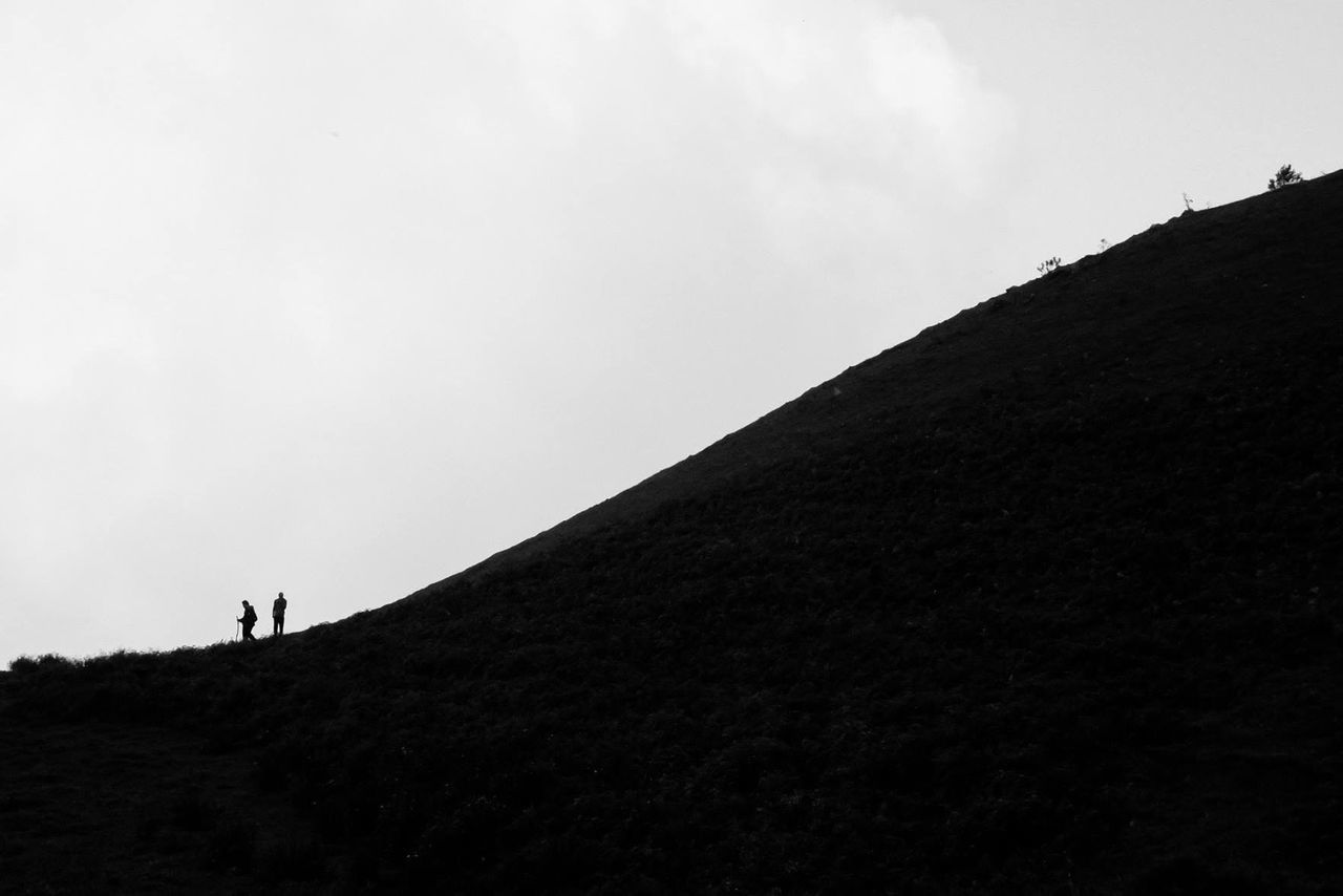 Silhouette friend standing on hill against sky