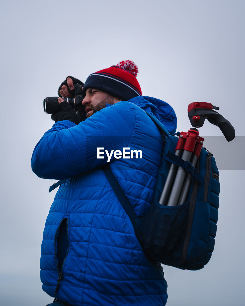 Side view of man photographing against sky