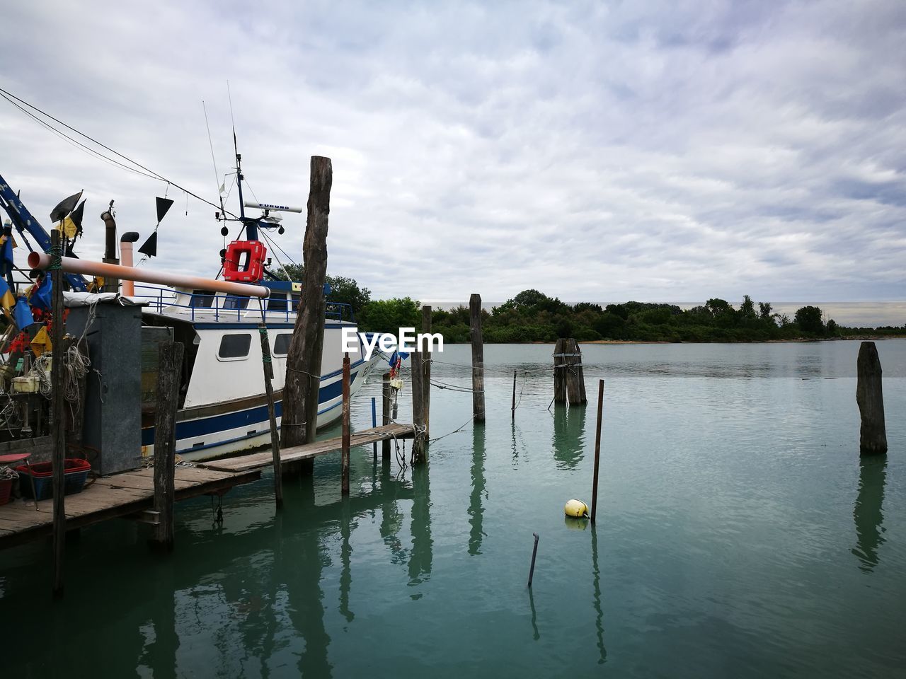 Boats in harbor against cloudy sky