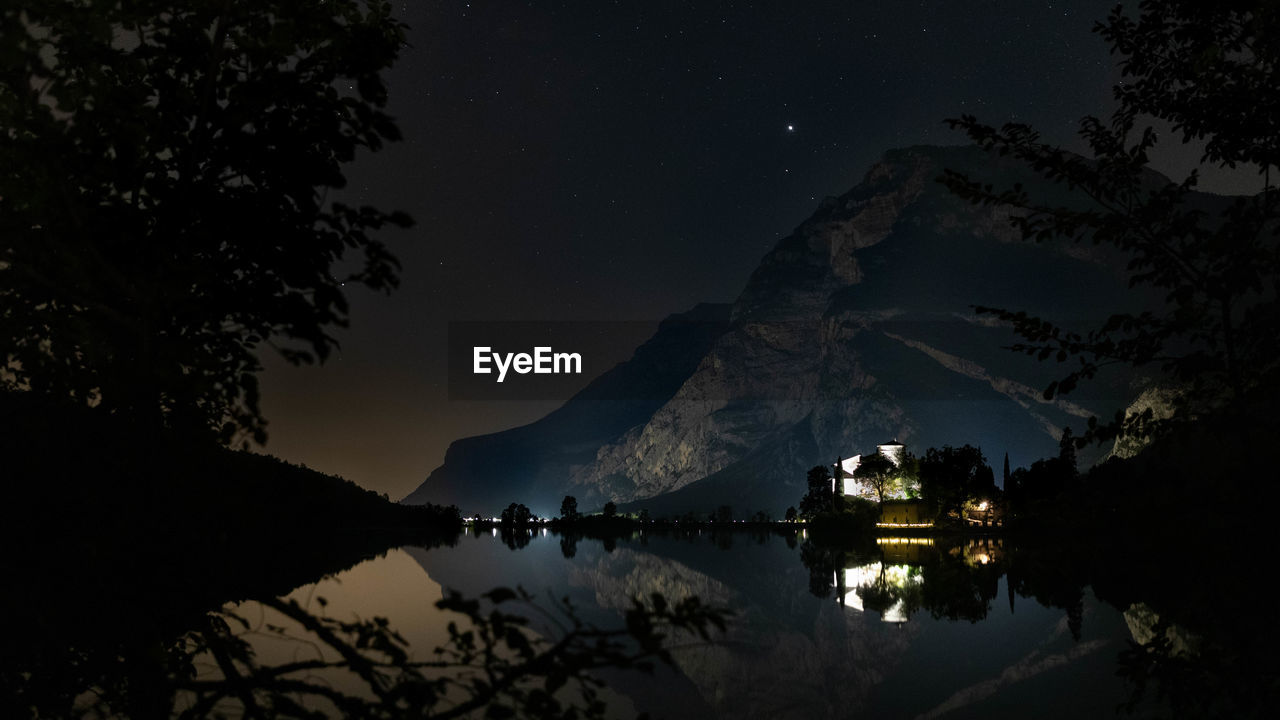 Toblino castle on lake toblino in the evening under the starry sky and mountain
