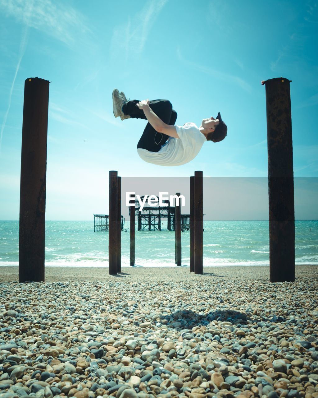 Man jumping on beach against sky