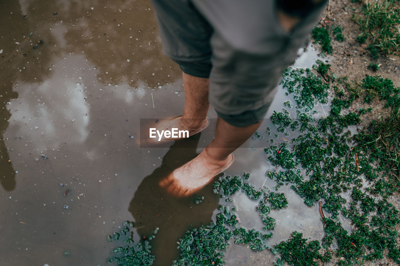 Low section of man standing in puddle