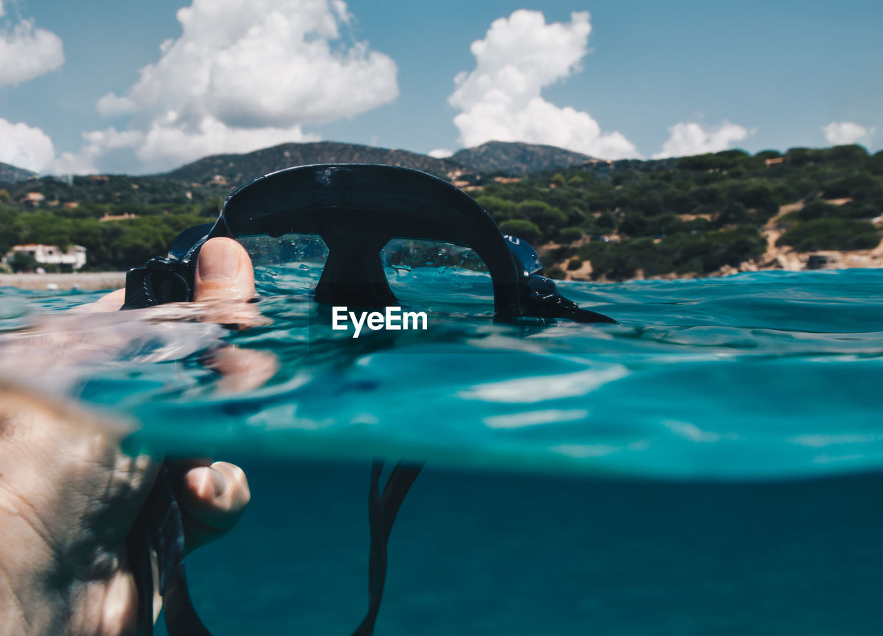 Cropped hand of man holding scuba mask in sea