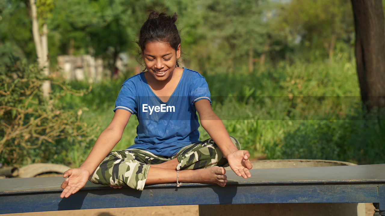 Positive cute little indian girl sitting on the roll mat. girls doing gymnastic exercises or exerc