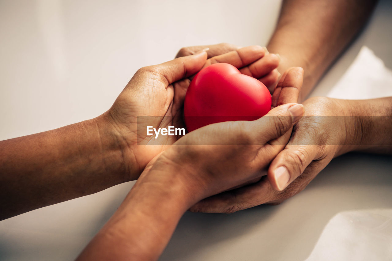 High angle view of people holding red heart shape toy on table