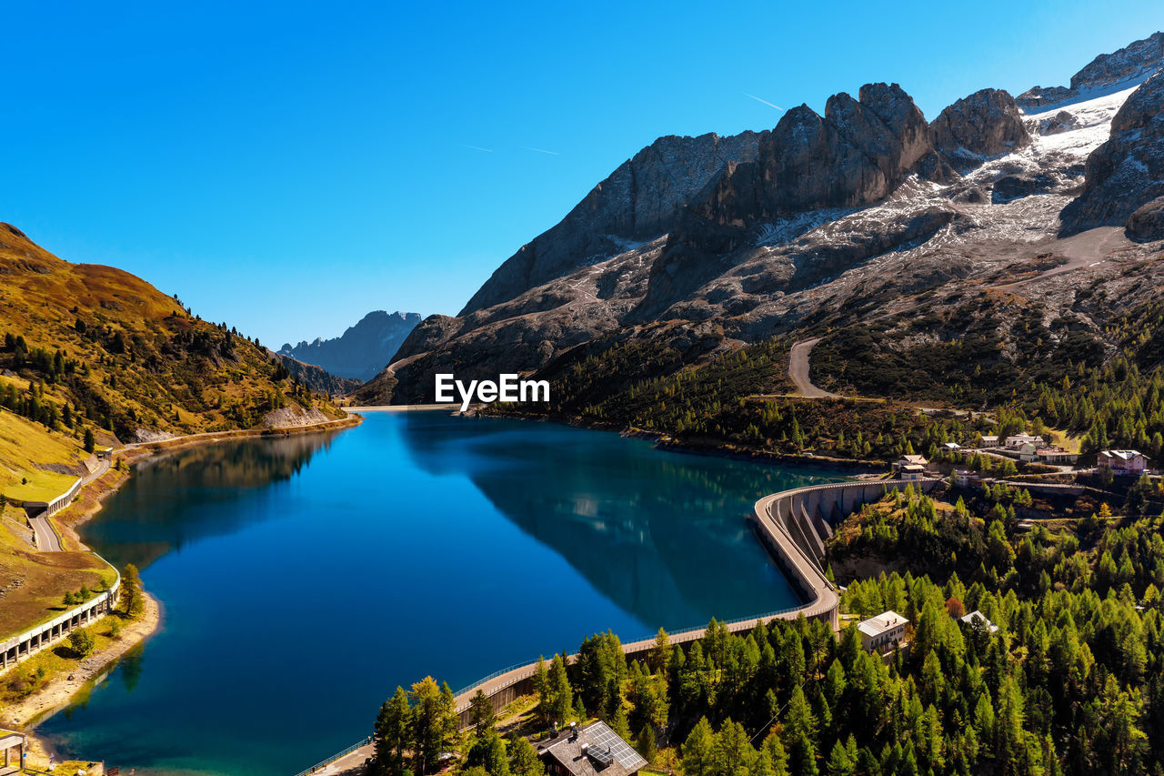 Scenic view of lake and mountains against clear blue sky