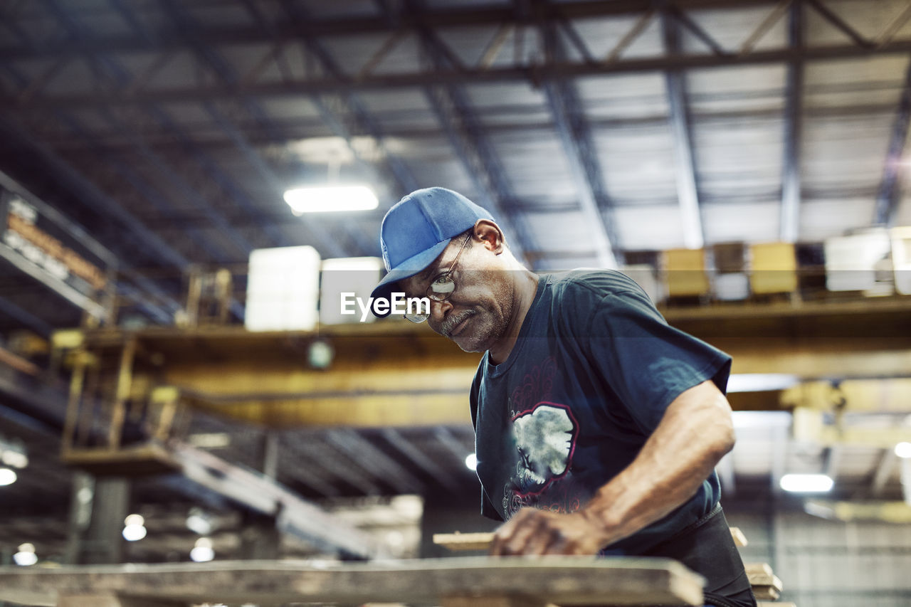 Serious worker working over wooden planks at industry