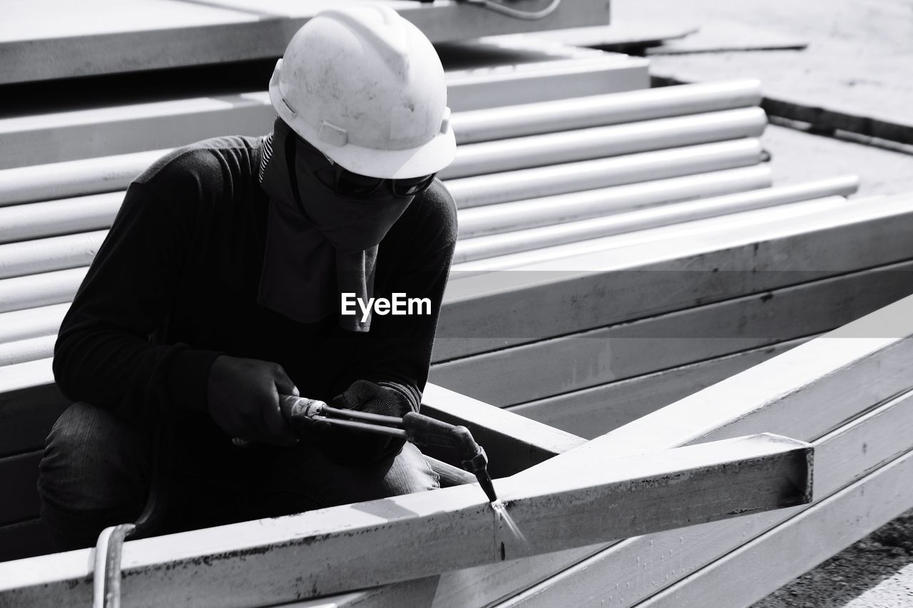 Manual worker welding with tool at construction site