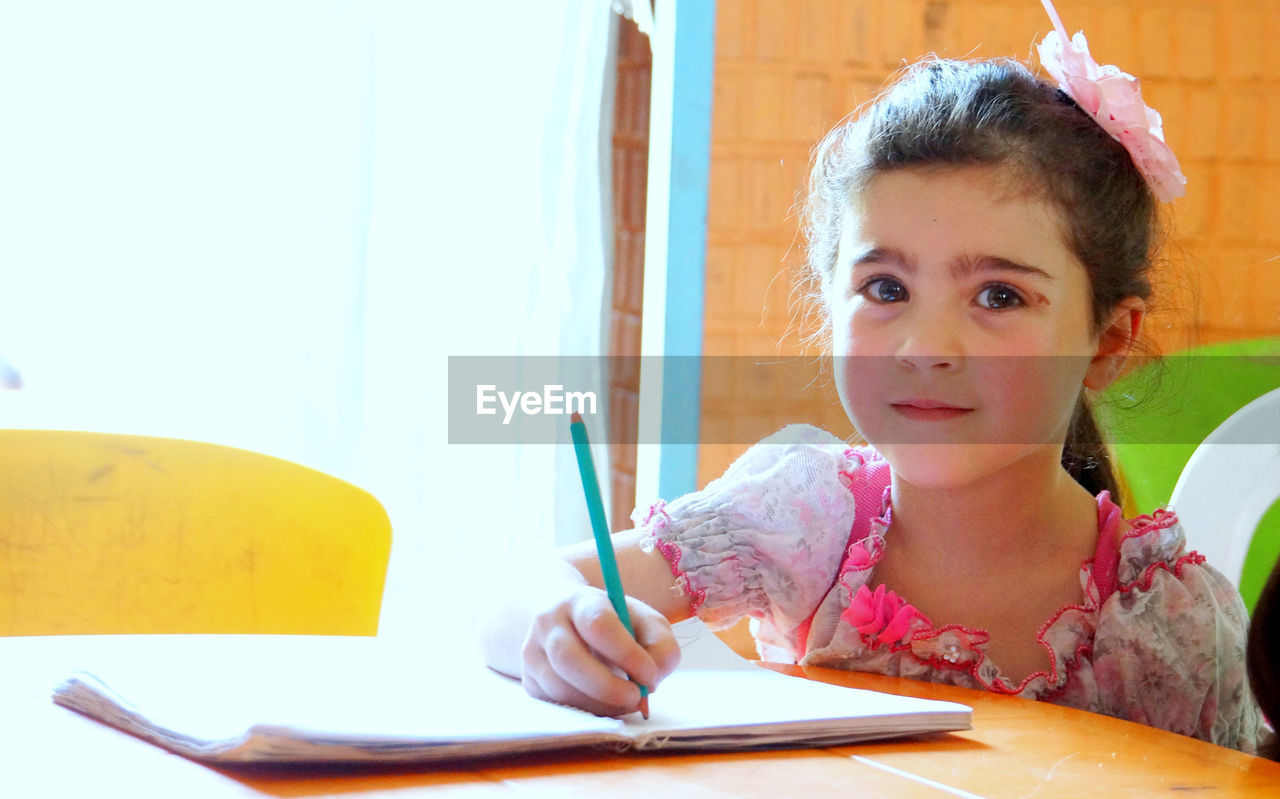 Portrait of girl writing in book at home