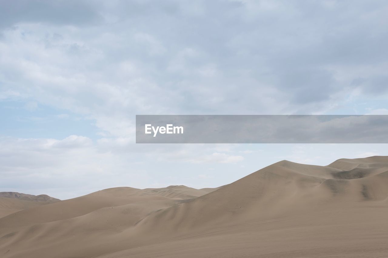 Scenic view of desert against cloudy sky