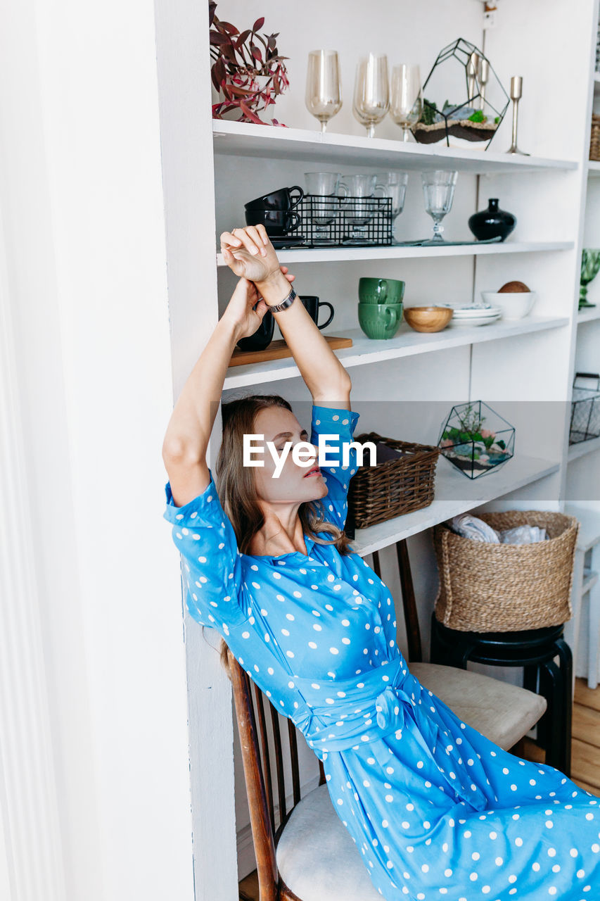 MIDSECTION OF WOMAN SITTING AT HOME