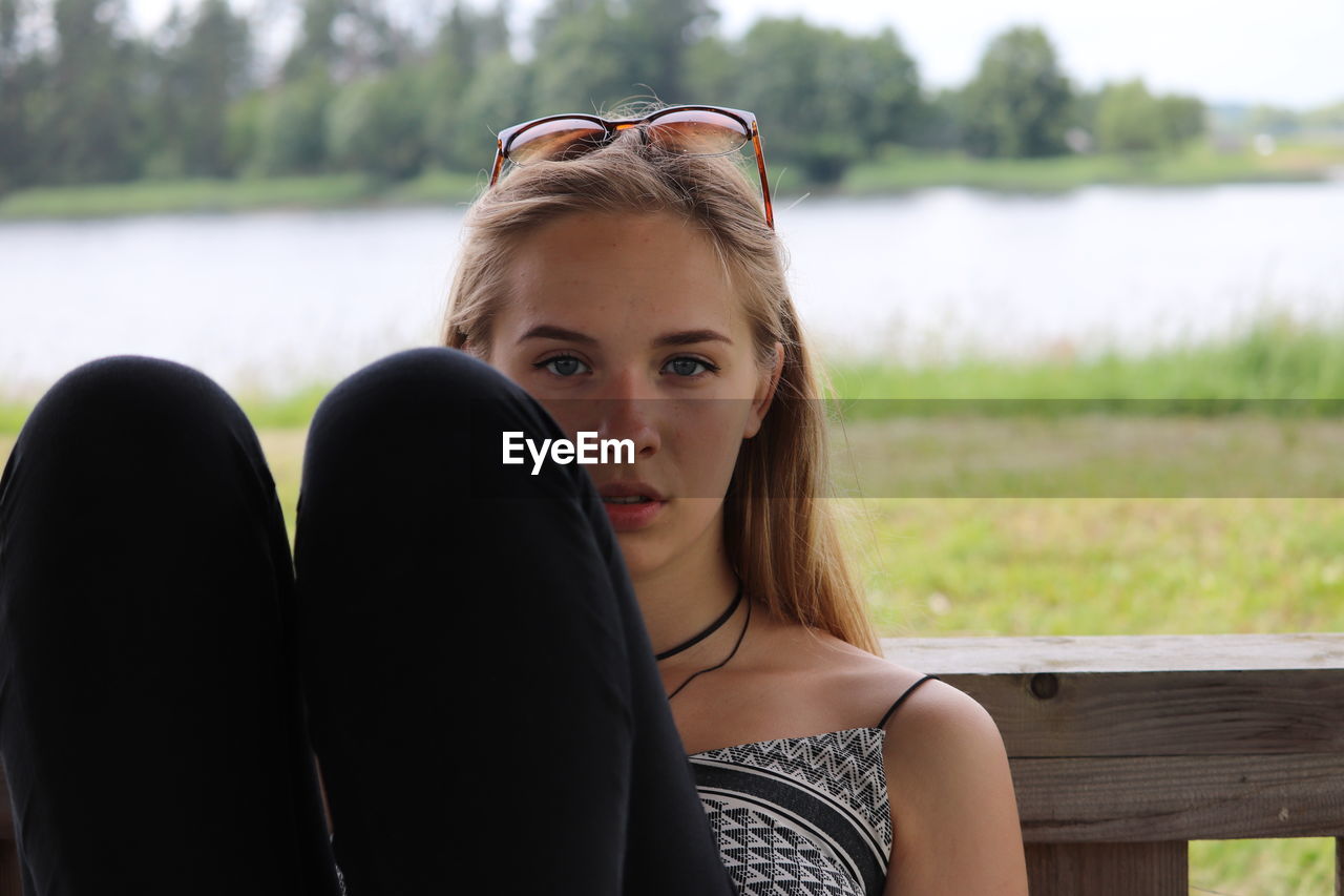 Portrait of woman sitting against lake