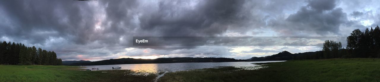 Panoramic shot of storm clouds over lake during sunset