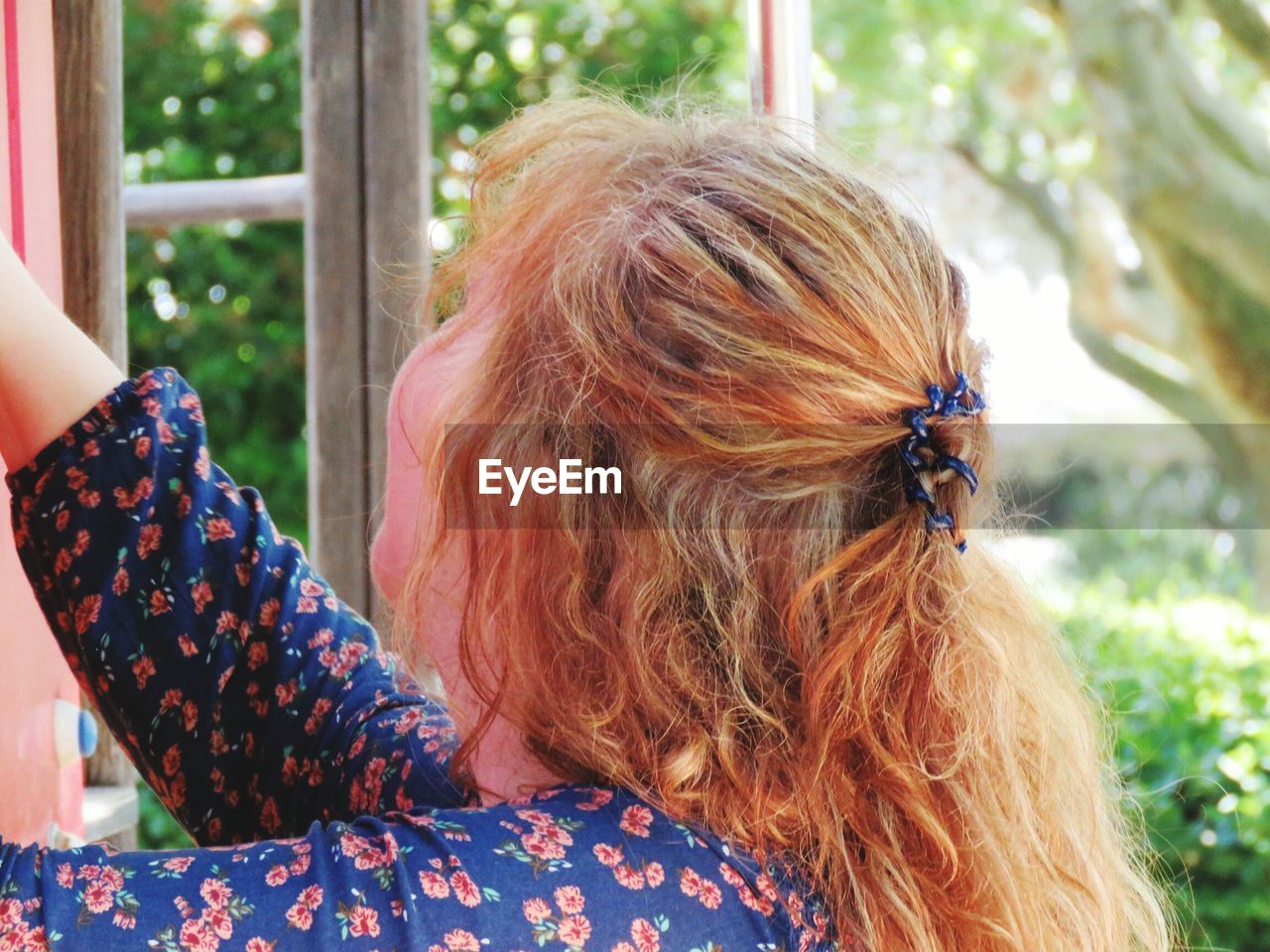 Side view close-up of young woman with long blond hair in yard