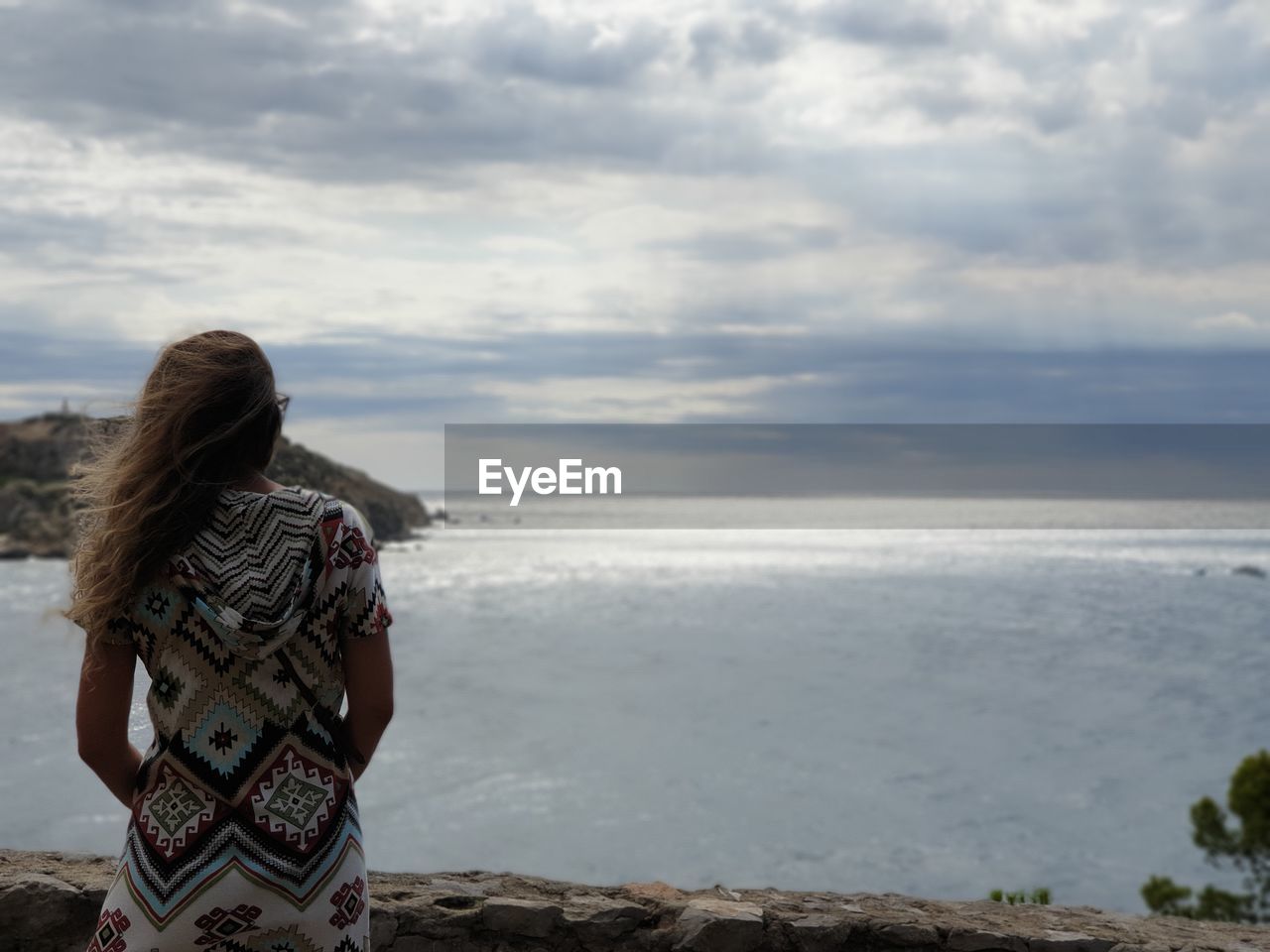 Rear view of woman standing by sea against sky