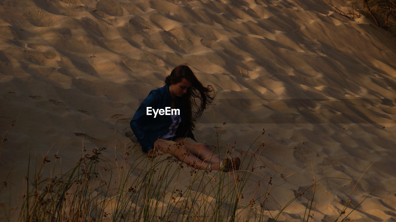 Woman sitting on sandy beach