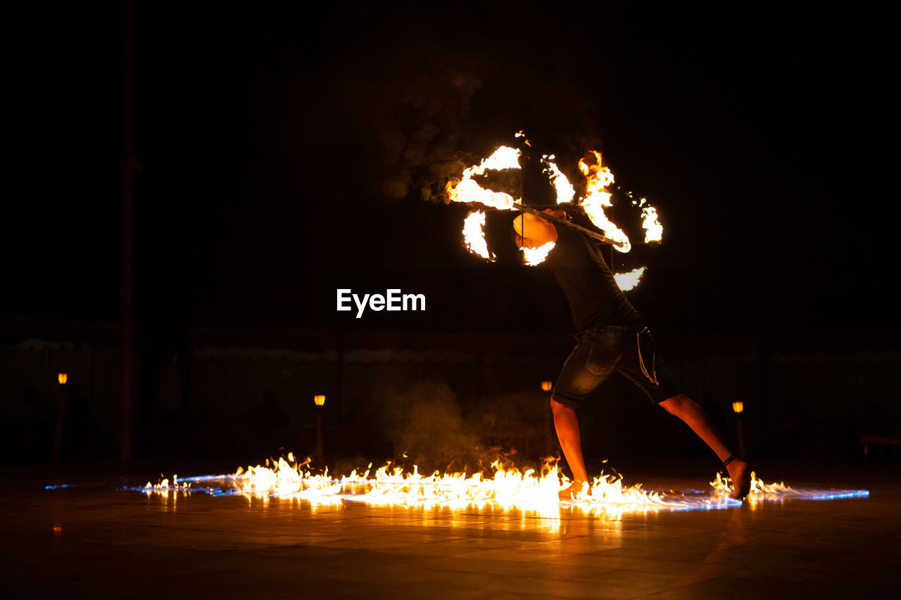 REFLECTION OF MAN ON ILLUMINATED FIRE IN DARK