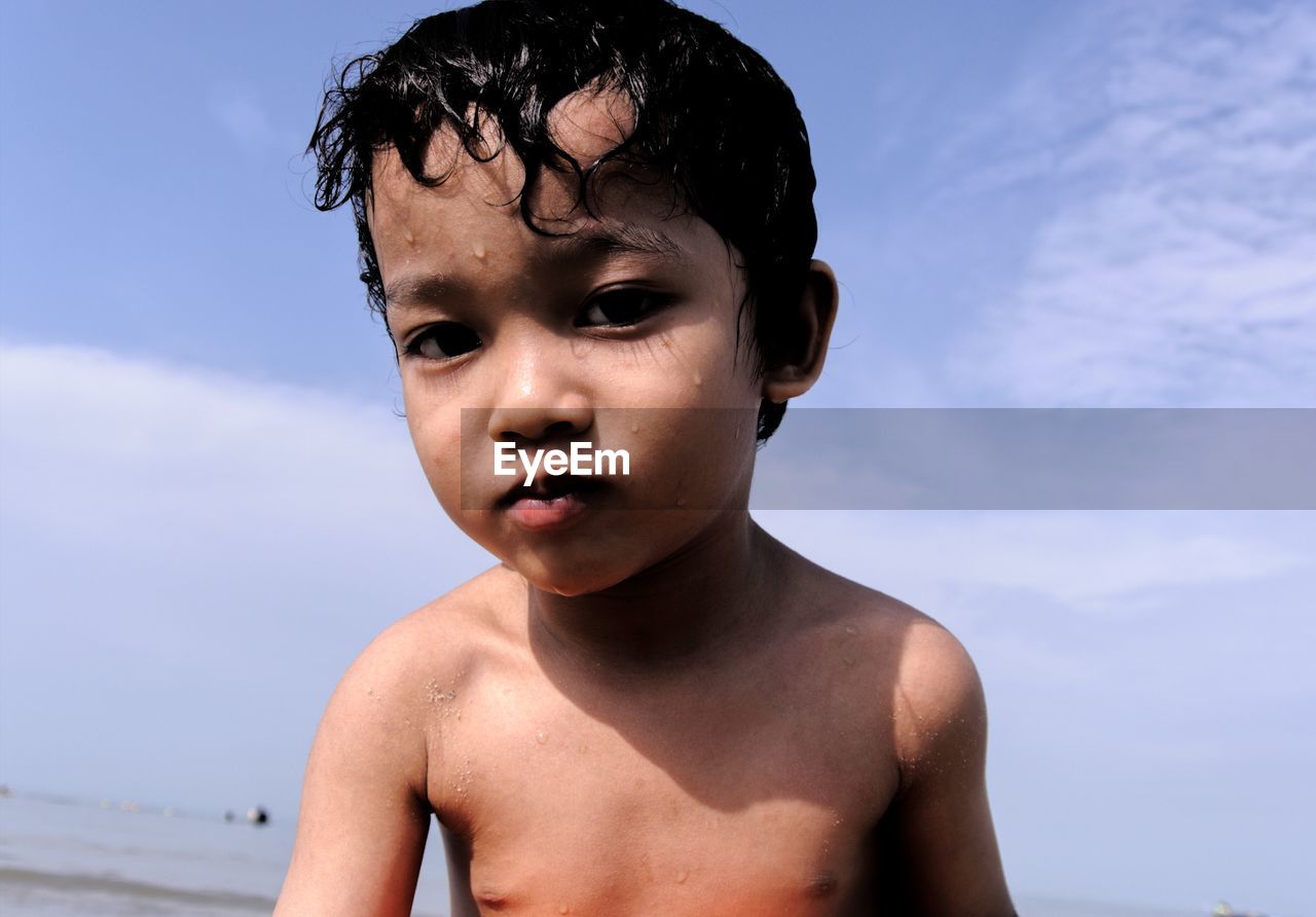 Portrait of shirtless boy against sky