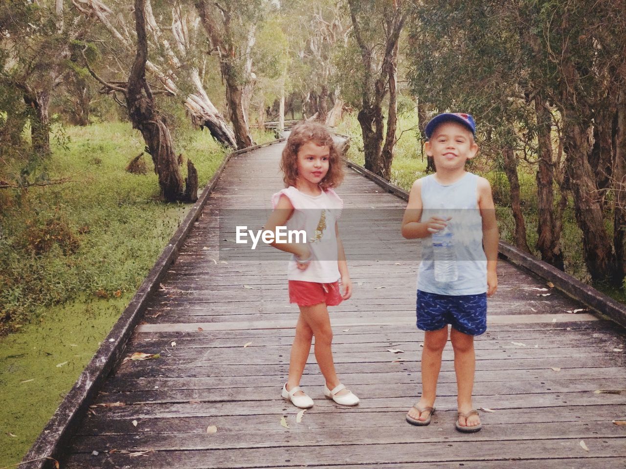 Portrait of smiling boy and girl standing against trees