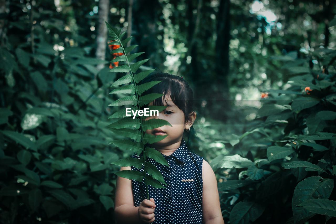 Portrait of girl holding leaves in forest