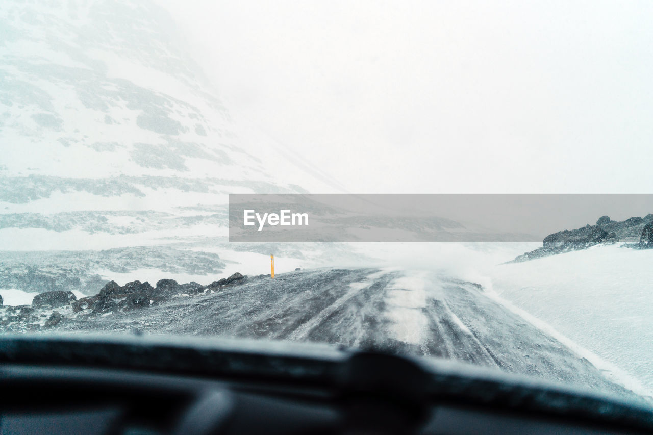 Scenic view of snowcapped mountains seen through car windshield