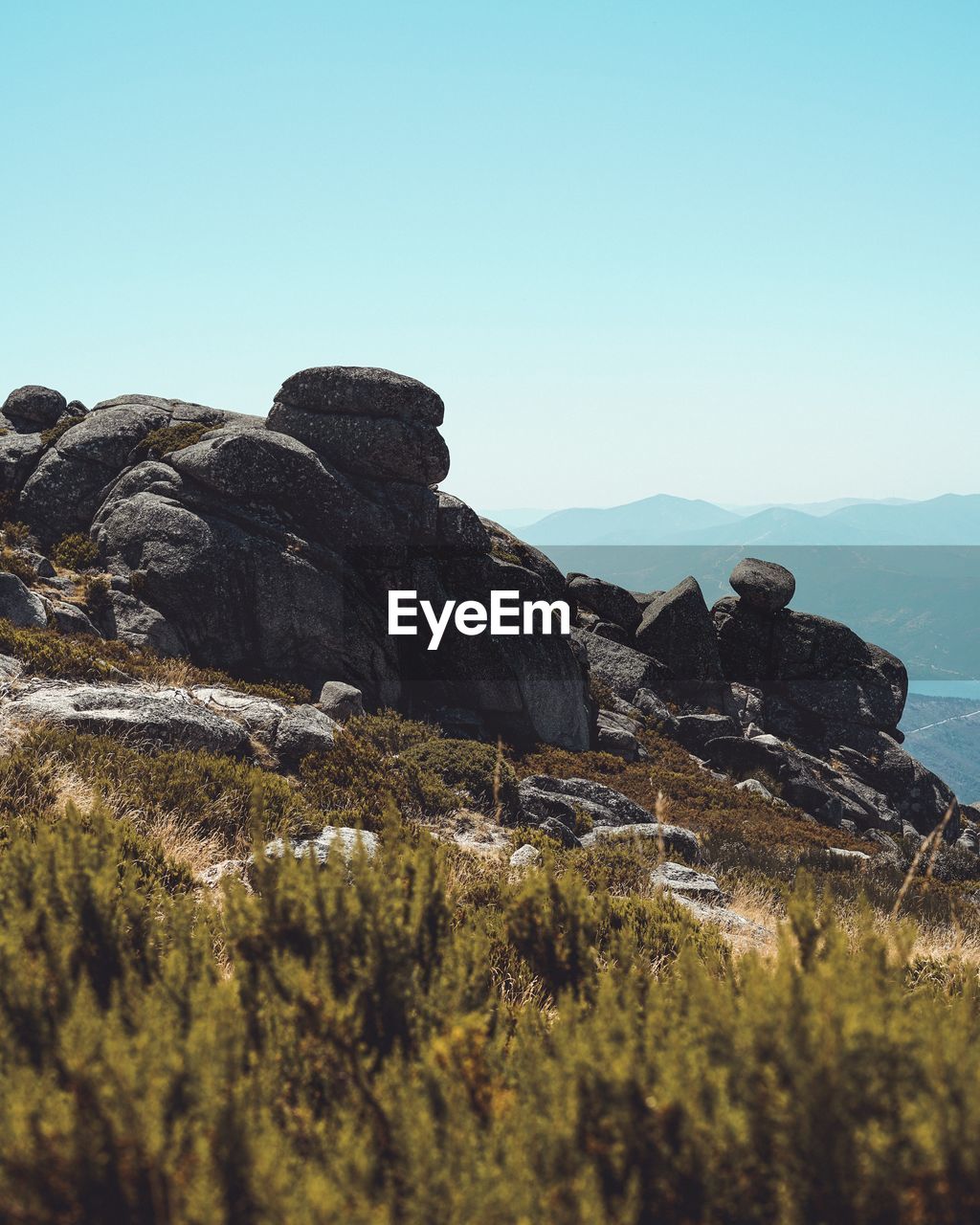 Scenic view of rocks by sea against clear sky